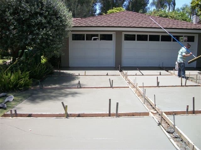 New concrete driveway being finished with a brick inlay border