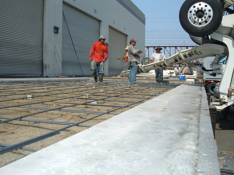 In-house concrete crew placing a reinforced concrete slab at a loading dock