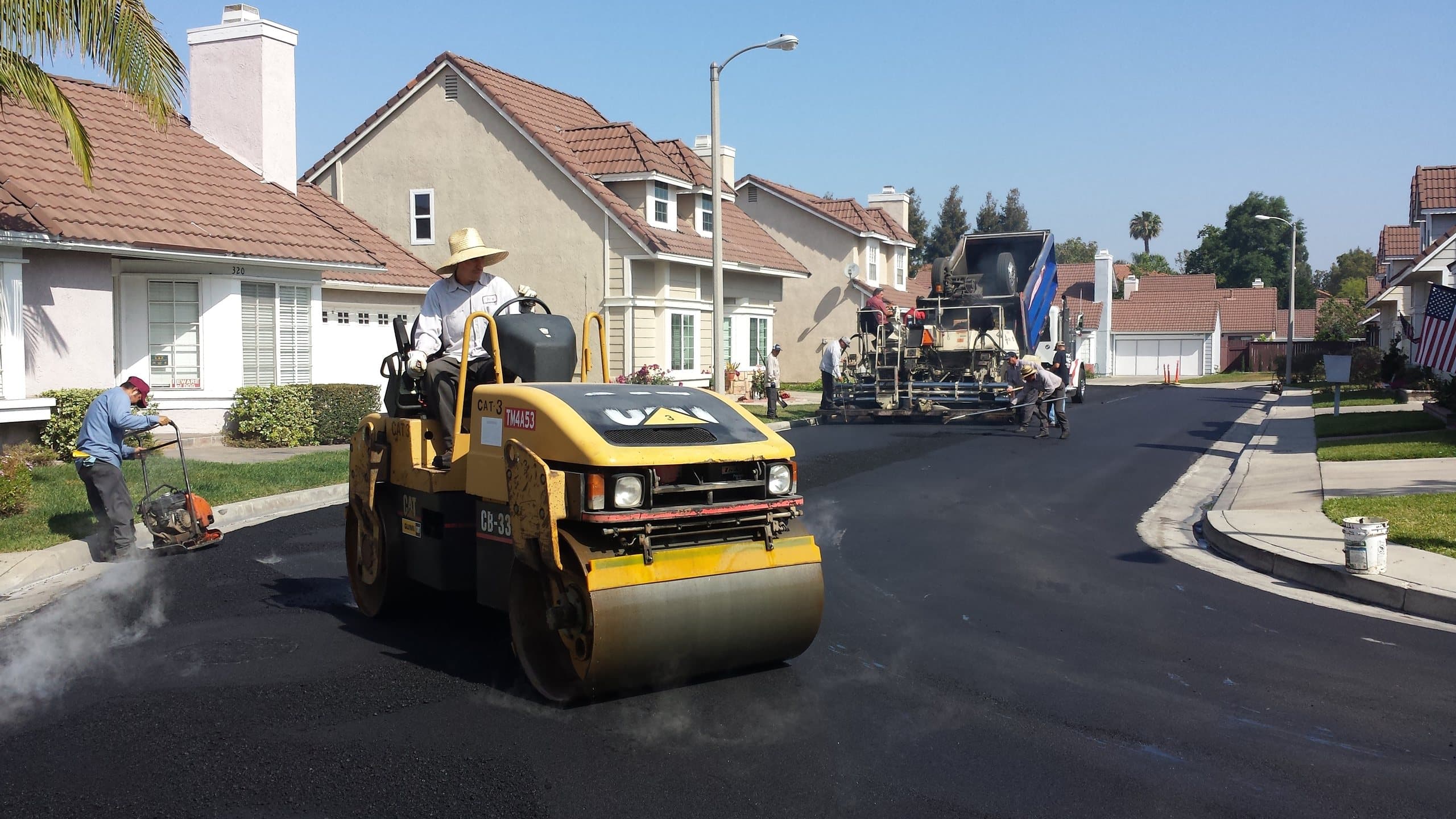 City Service Paving crew compacting fresh asphalt with a double-drum roller on a residential street