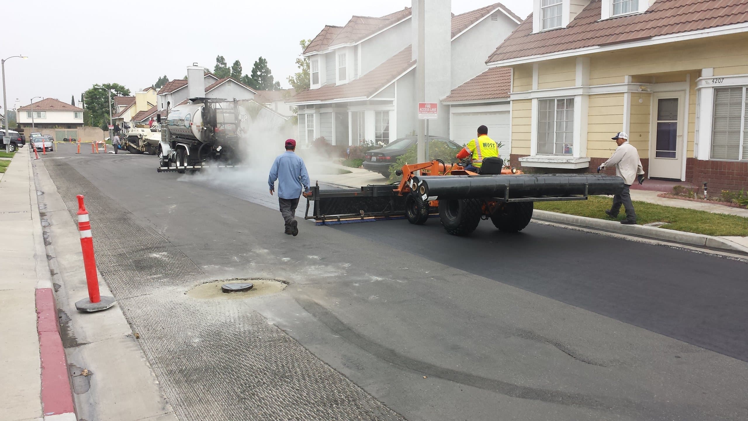 Crew preparing a residential street with traffic cones in place before paving