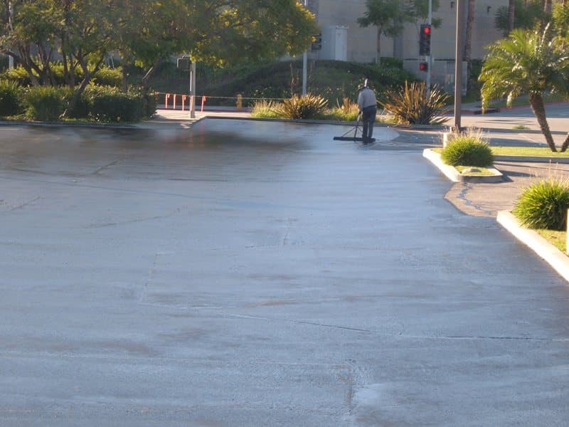 Seal coat being applied across an apartment community drive