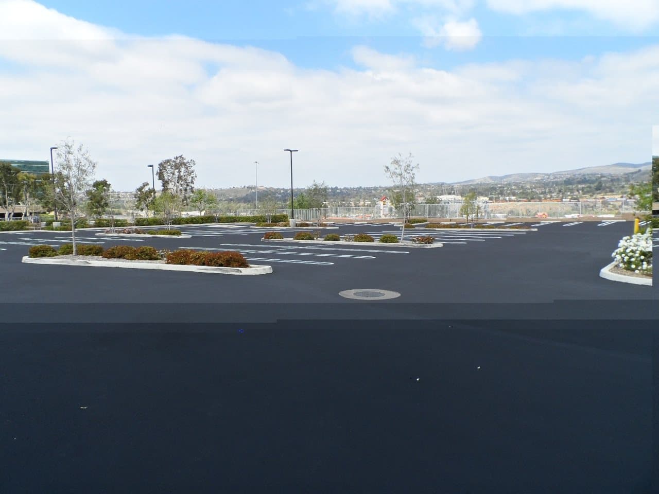 Large commercial parking lot after seal coating, with hills in the background